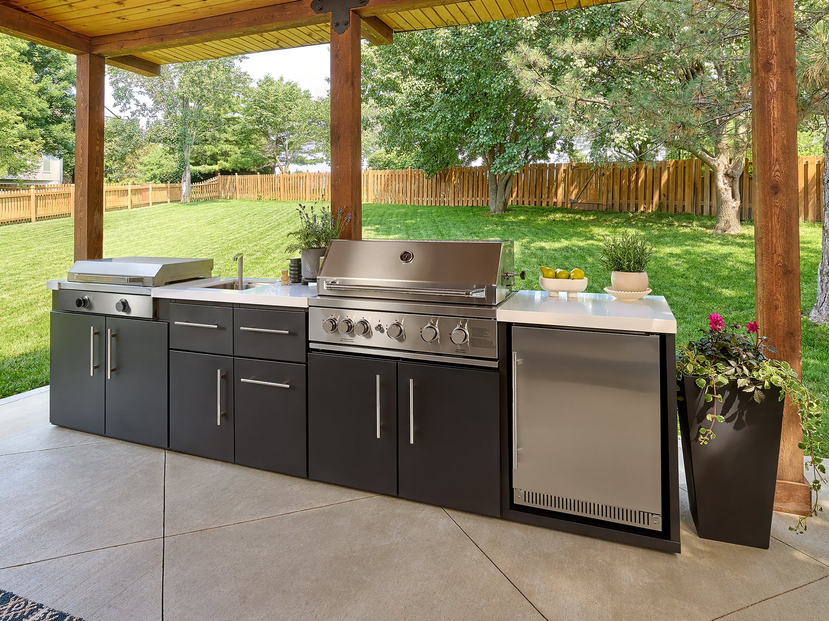 Emory outdoor kitchen with grill griddle combo, engineered stone countertop, stainless steel fridge.
