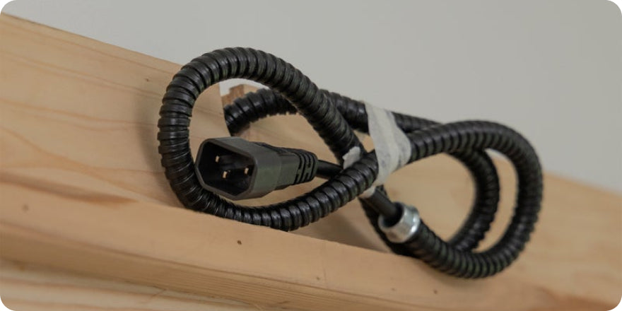 Coiled black electrical cable on a wooden surface