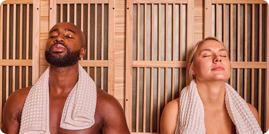 Two people relaxing in a sauna with wooden walls.