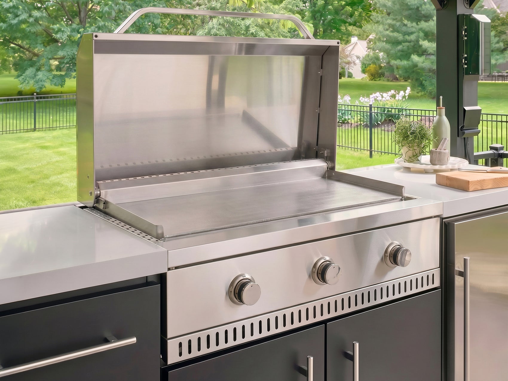 Outdoor griddle made from stainless steel with the lid open and three control knobs in the Lancaster Linear kitchen.