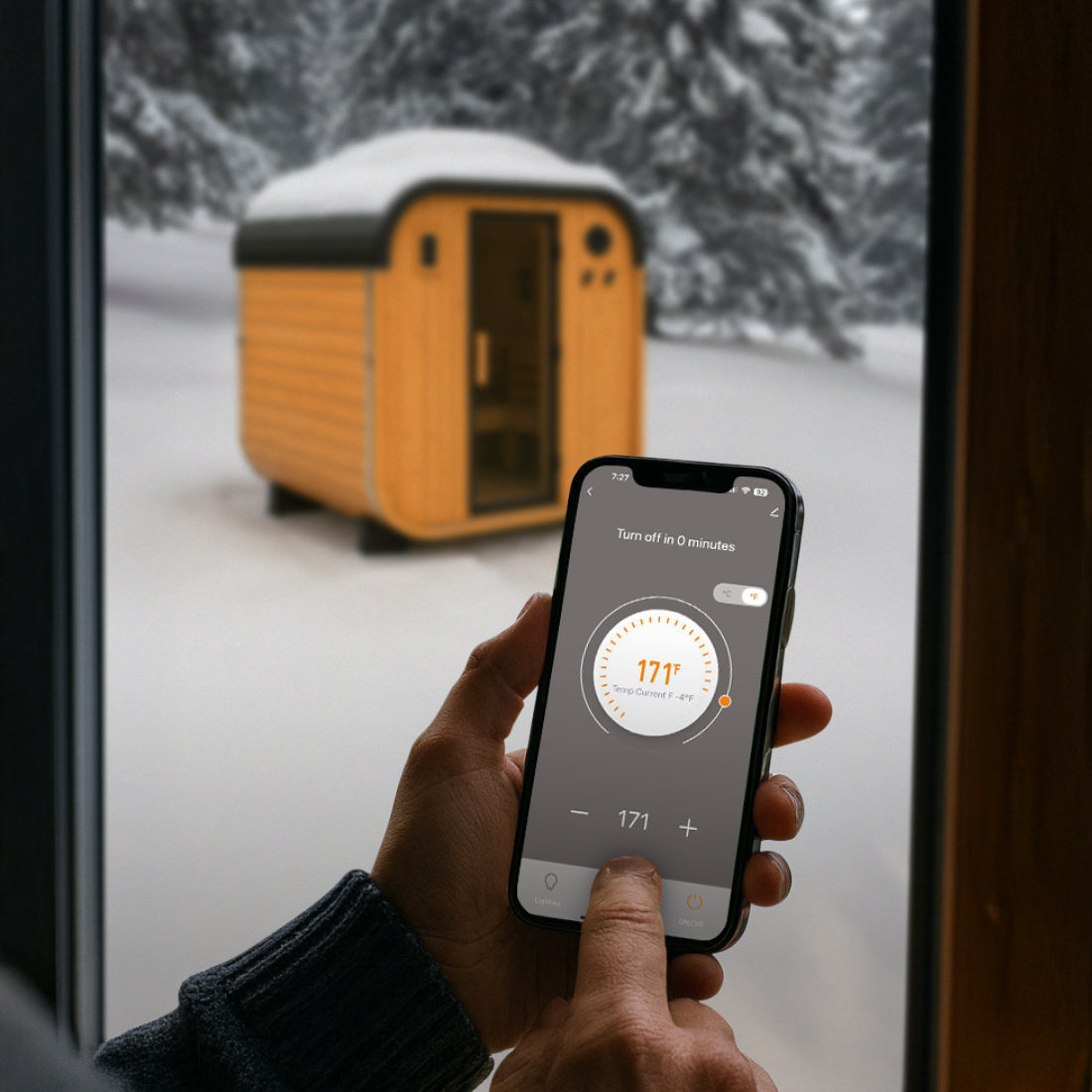 Person inside using Tuya Smart App on smartphone to control Lennon Outdoor Sauna temperature in a snowy outdoor setting