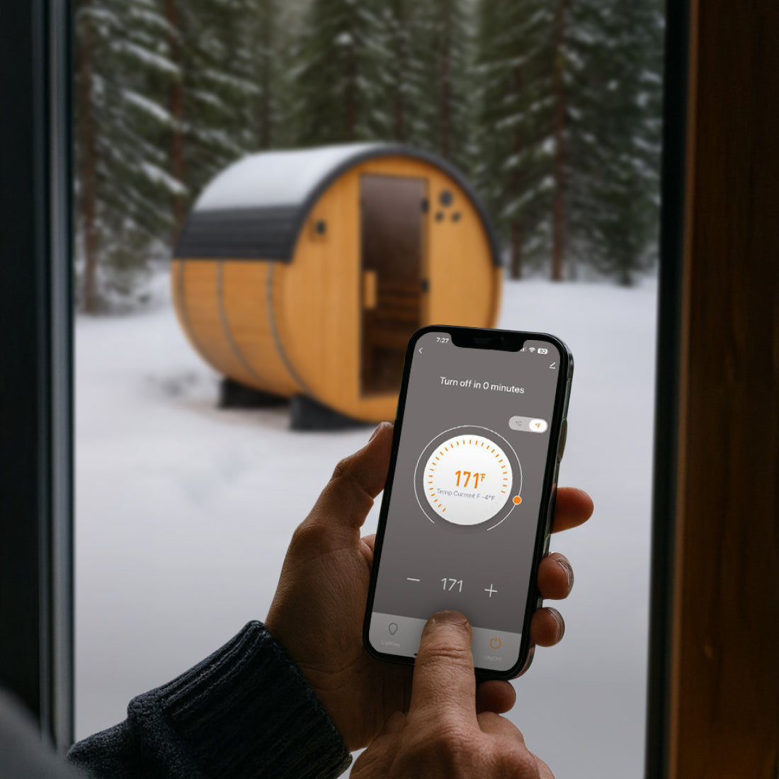 Person inside using Tuya Smart App on smartphone to control Paxton Outdoor Sauna temperature in a snowy outdoor setting