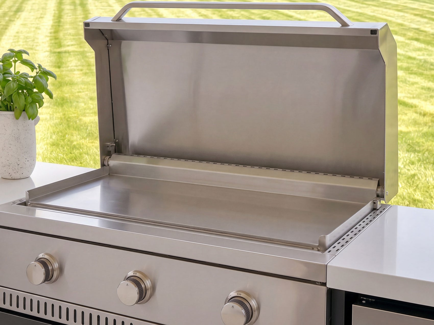 Stainless steel griddle with lid in a outdoor kitchen with countertop.