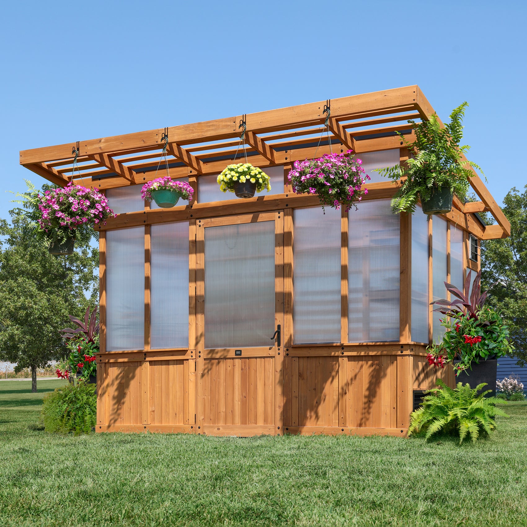 Backyard Discovery Poppy 11x7 greenhouse with a pergola overhang and hanging flower baskets.