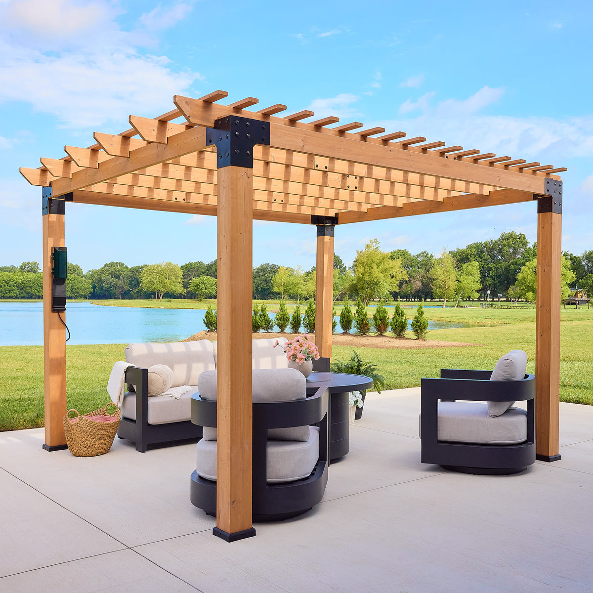 Cedar pergola with open purlin roof and black steel corner brackets staged over a patio beside a lake.