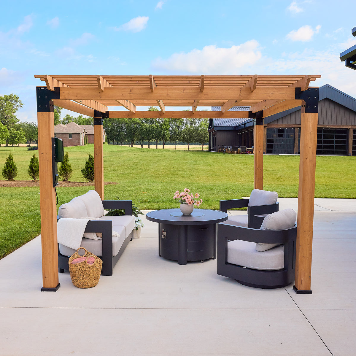 Open-slat purlin roof and cedar posts framing a freestanding outdoor pergola over a paved patio.