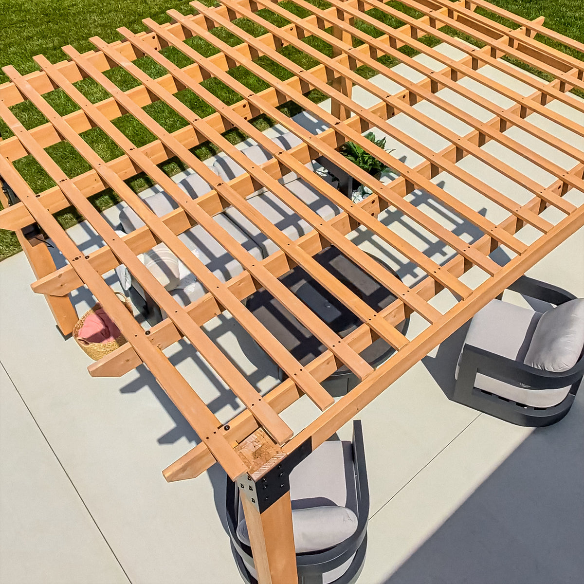 Layered open-slat purlin roof of a slatted pergola casting filtered shade across a paved patio below.