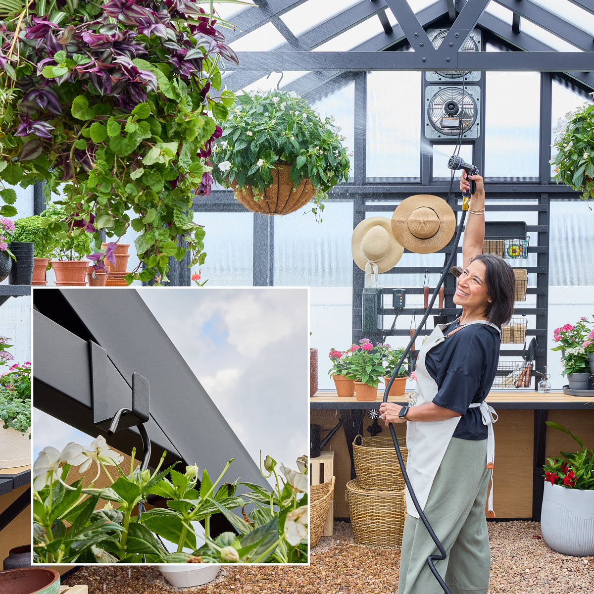 Woman watering hanging plants inside a black powder-coated steel greenhouse.