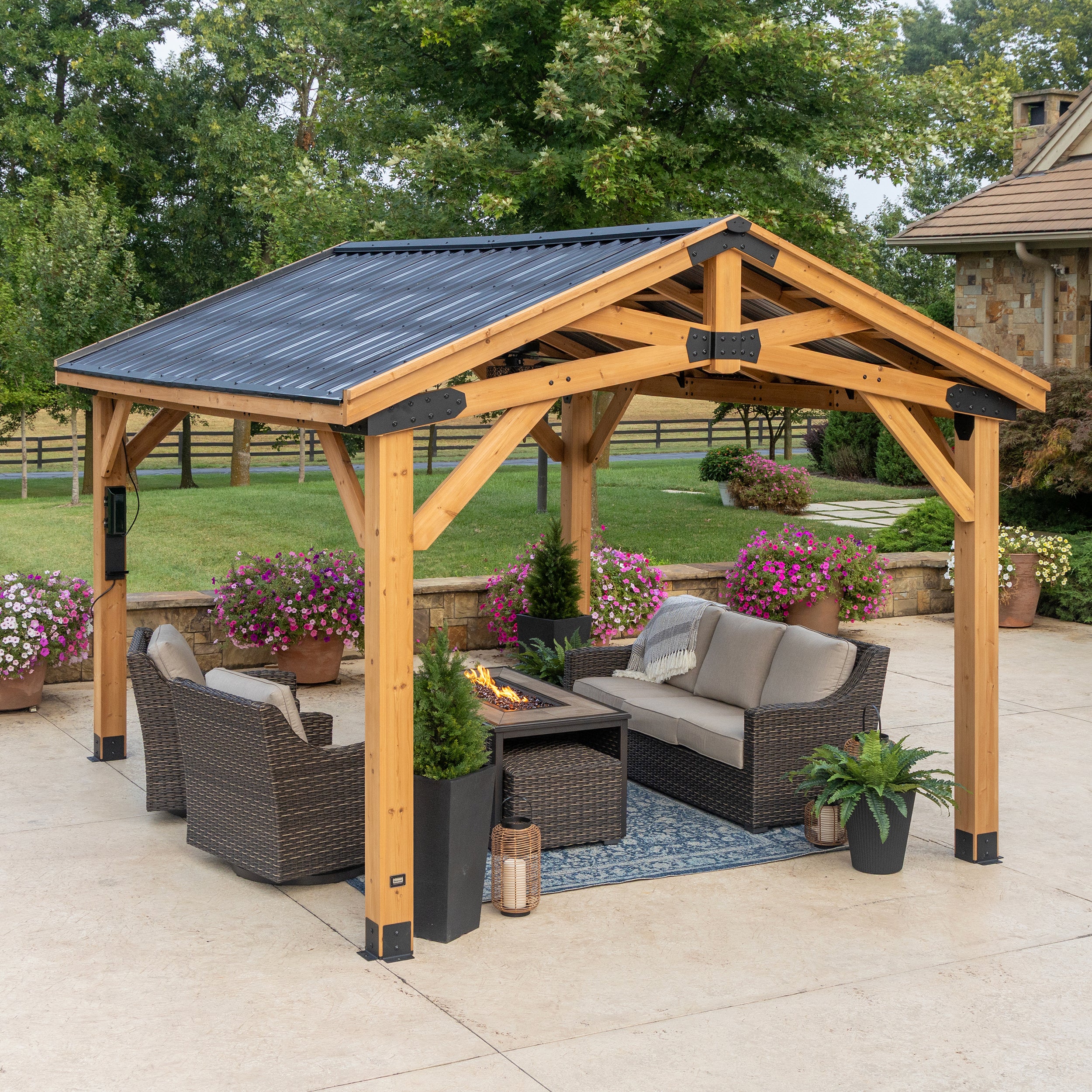Steel roof gazebo with cedar timber frame and arched trusses sheltering patio seating area in backyard.