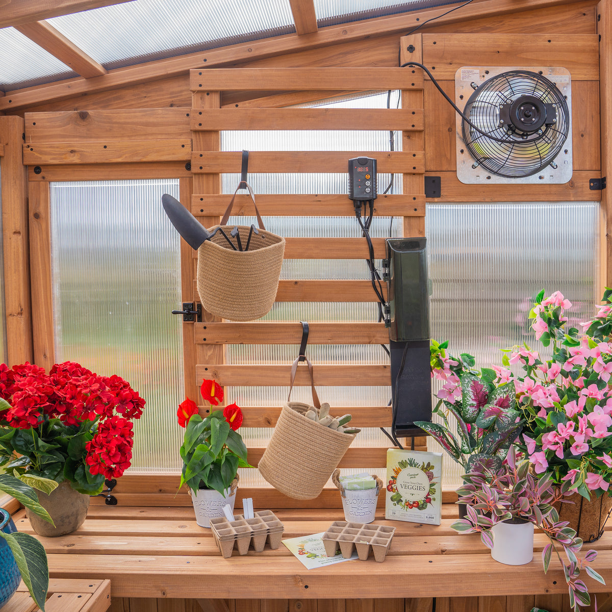 Slat wall organizer with hanging baskets, tools, thermostat, exhaust fan, and flowering plants on cedar staging bench.