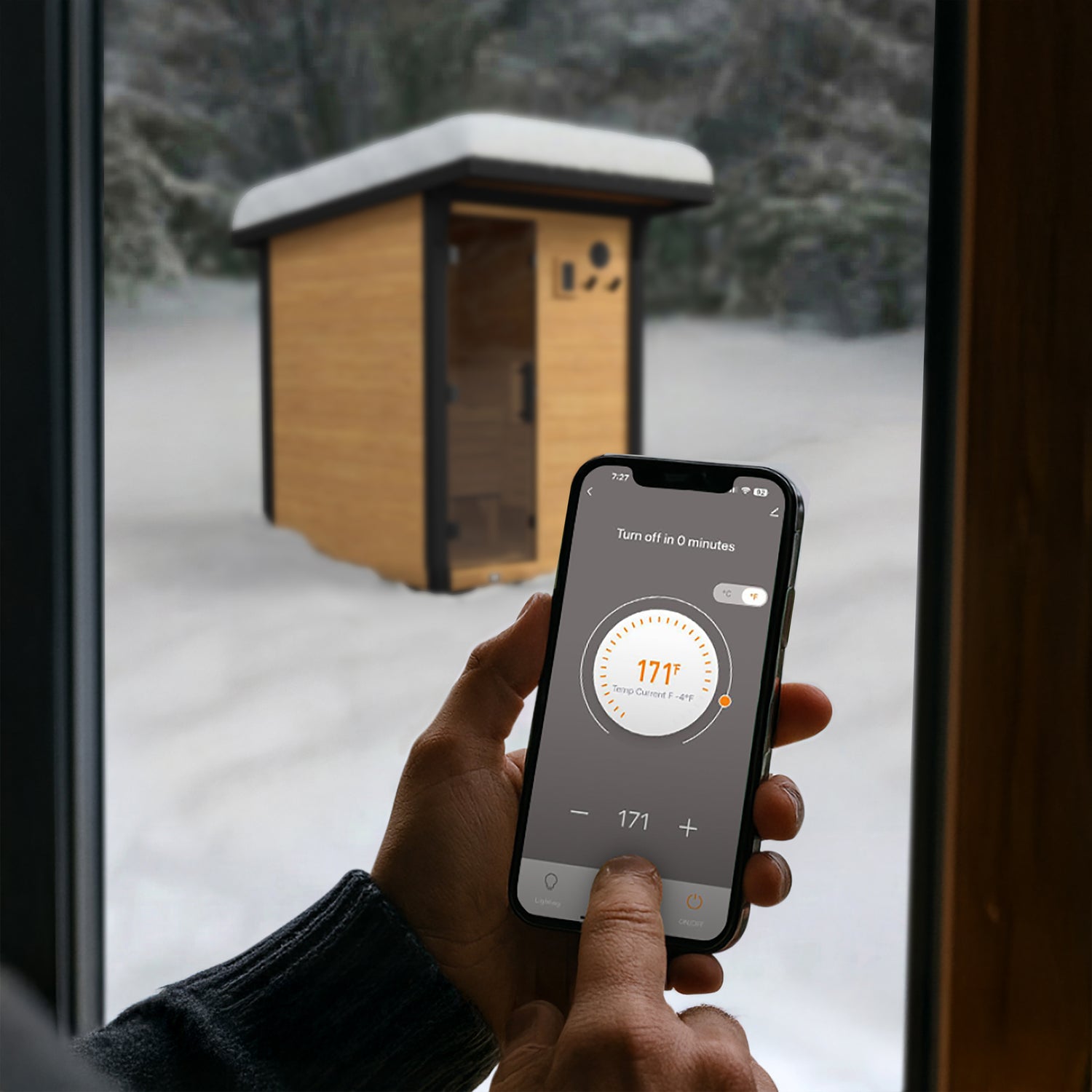 Person using a smartphone Tuya Smart mobile app to remotely control preheating of their outdoor traditional saunas from the comfort of their living room, alleviating needing to go outside multiple times to manually preheat your sauna.