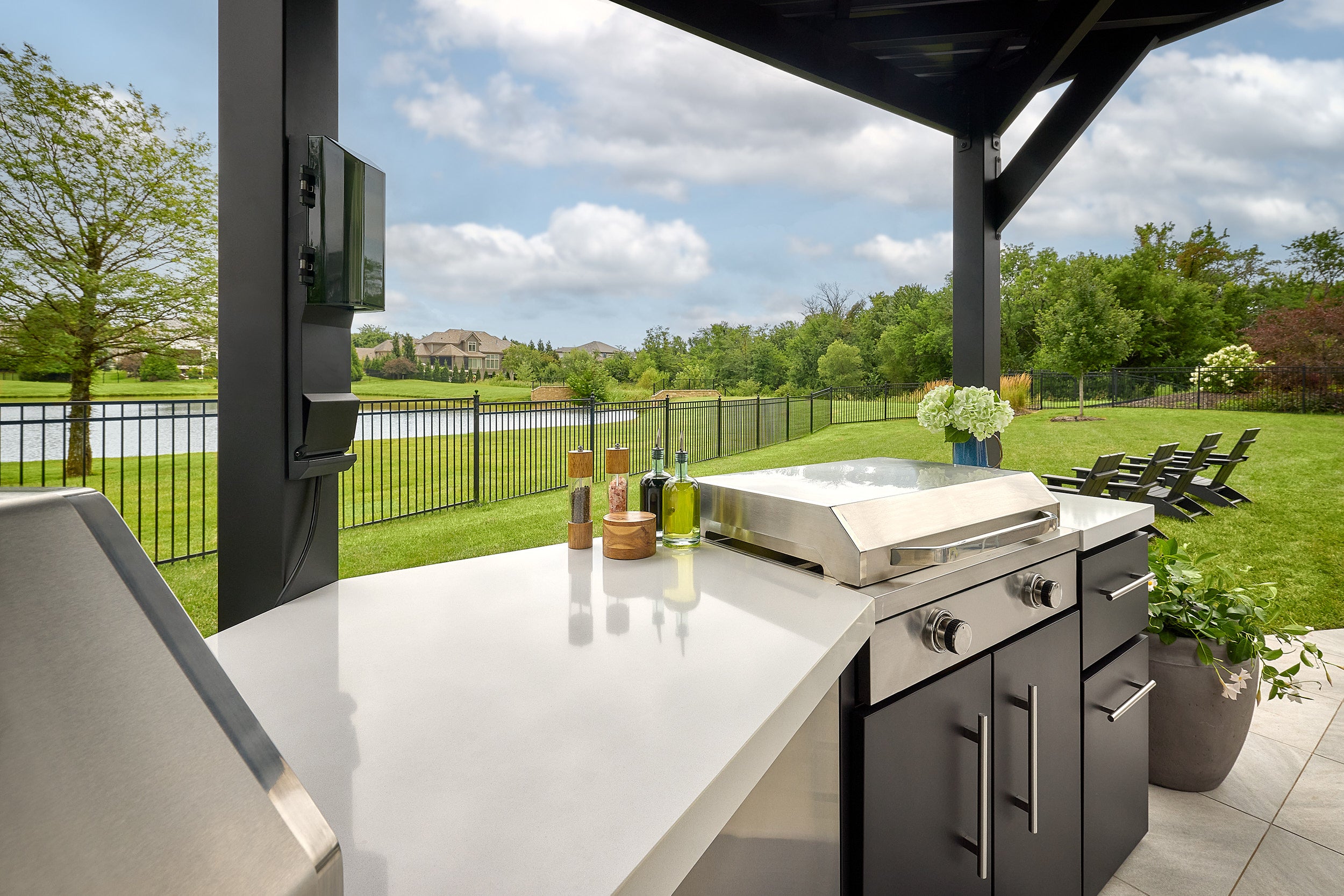Edgemont Cove Outdoor Kitchen lower cabinet door open revealing built-in paper towel holder with roll installed, pizza oven and grill visible in background