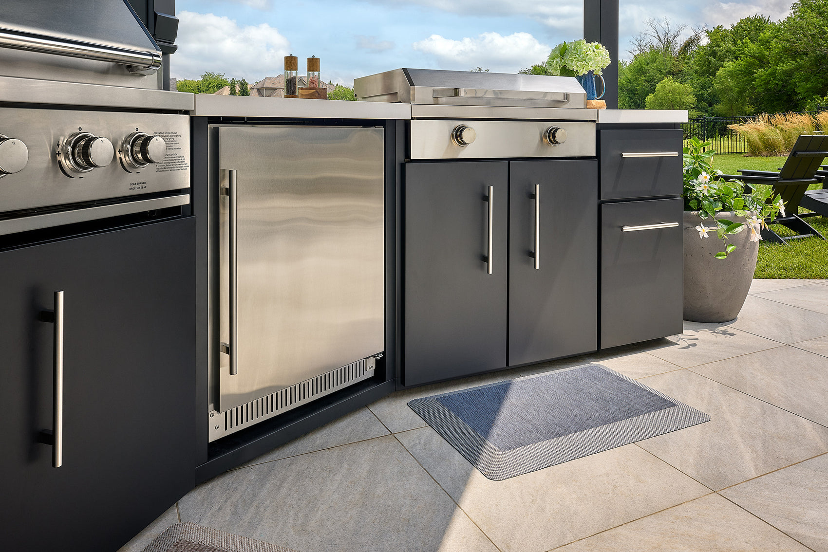 Edgemont Cove Outdoor Kitchen stainless steel pizza oven with door open and pizza visible inside on stone deck, with chimney stack above