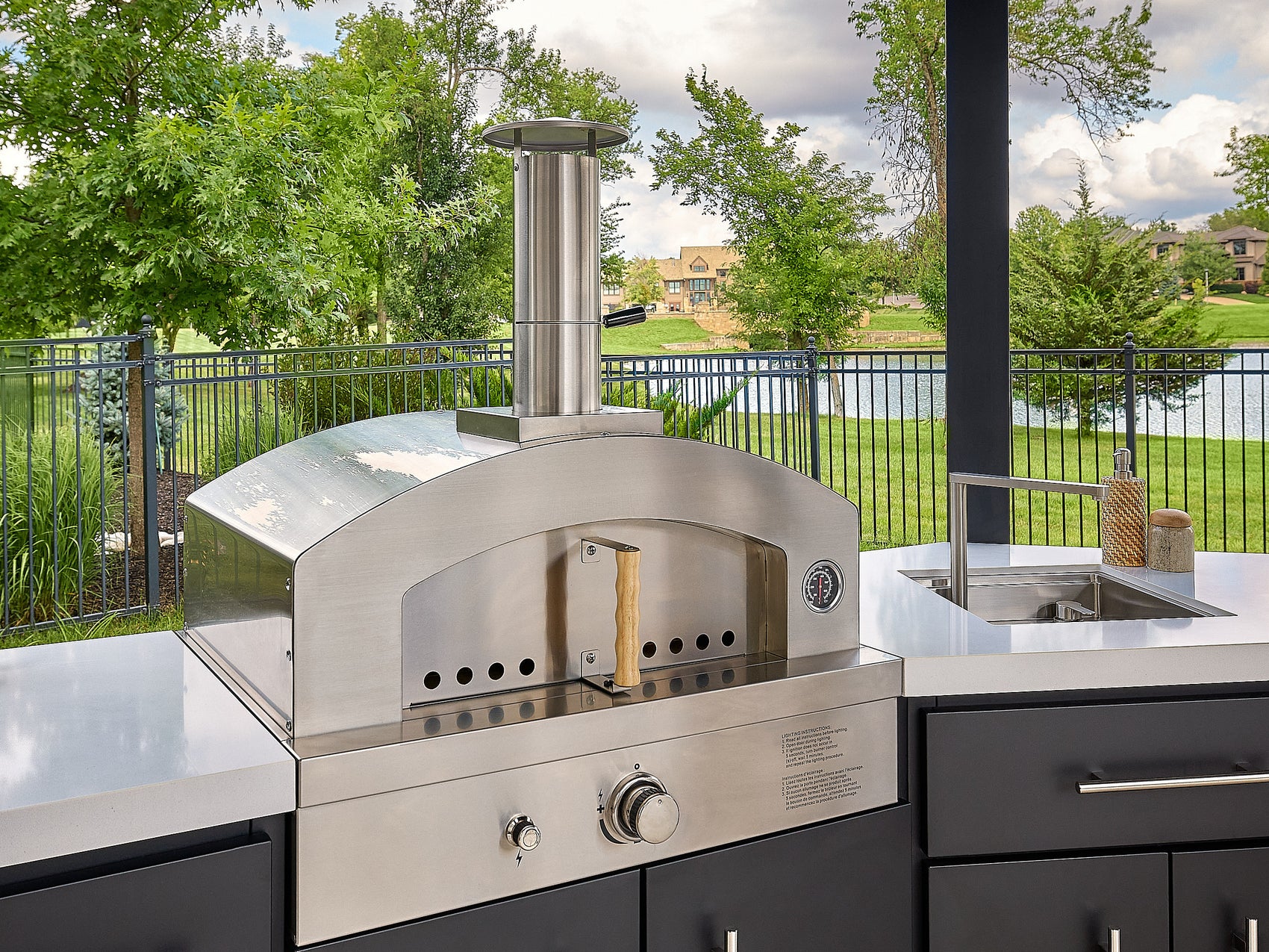 Edgemont Cove Outdoor Kitchen post-mounted weatherproof power port open with tablet on charging bracket and blender plugged into outlet on countertop