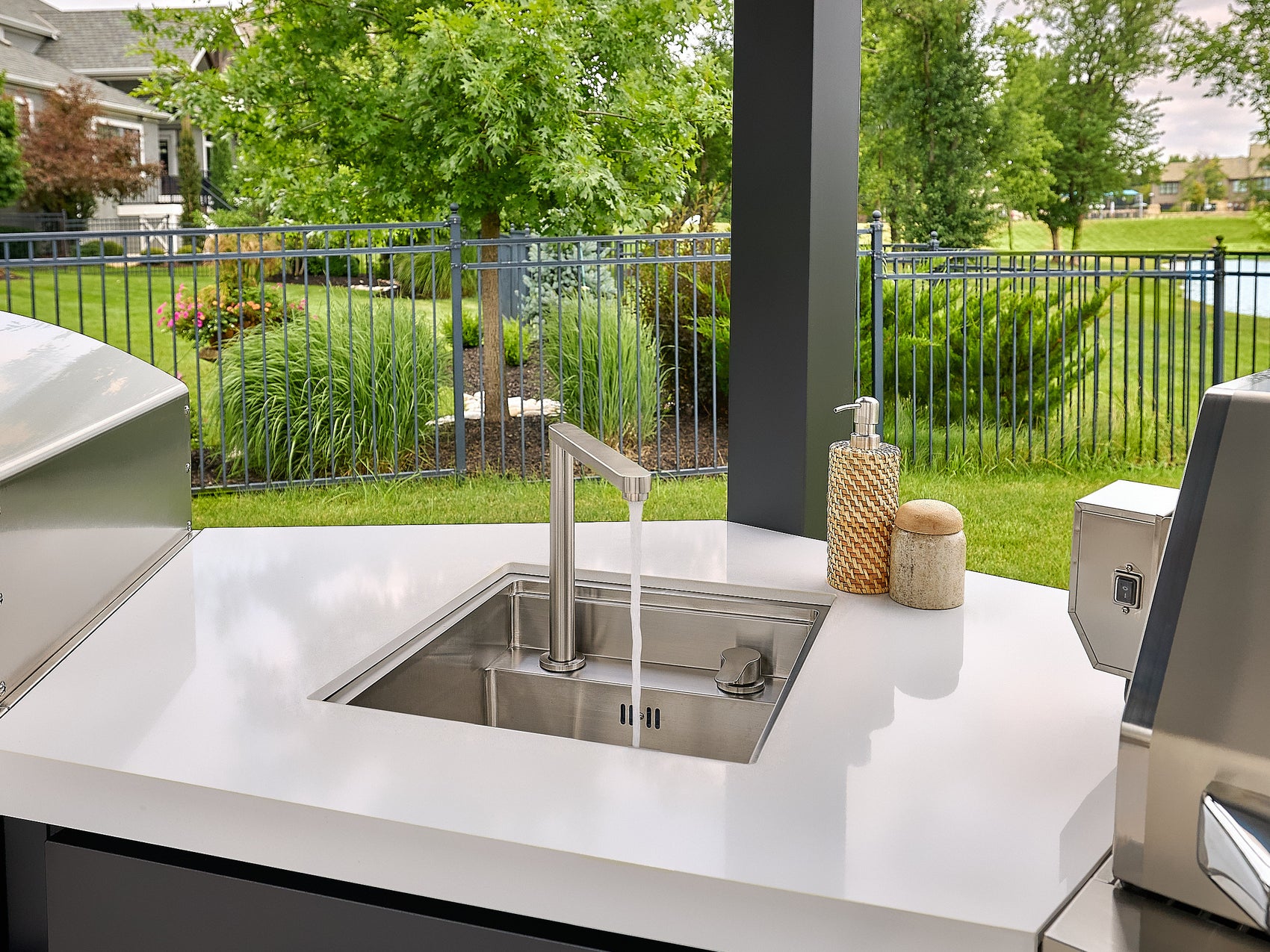 Edgemont Cove Outdoor Kitchen stainless steel pizza oven with door closed and wood-handle door latch, chimney stack above