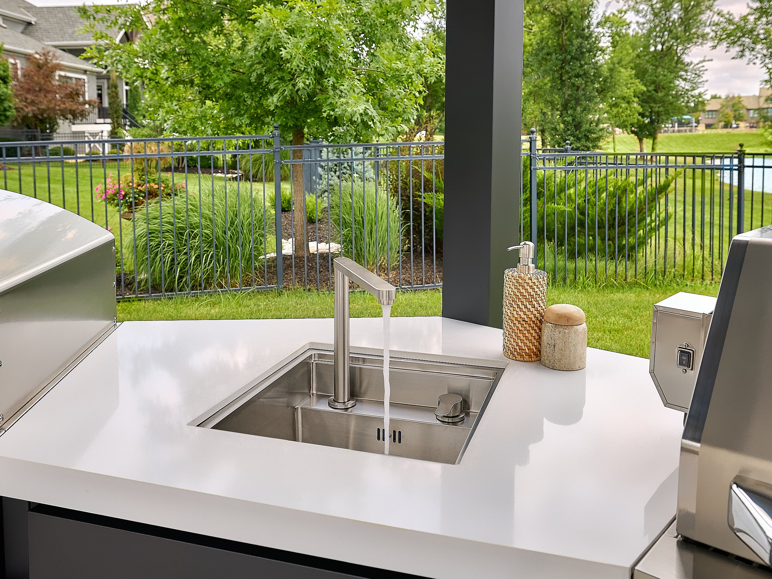 Edgemont Cove Outdoor Kitchen stainless steel pizza oven with door closed and wood-handle door latch, chimney stack above