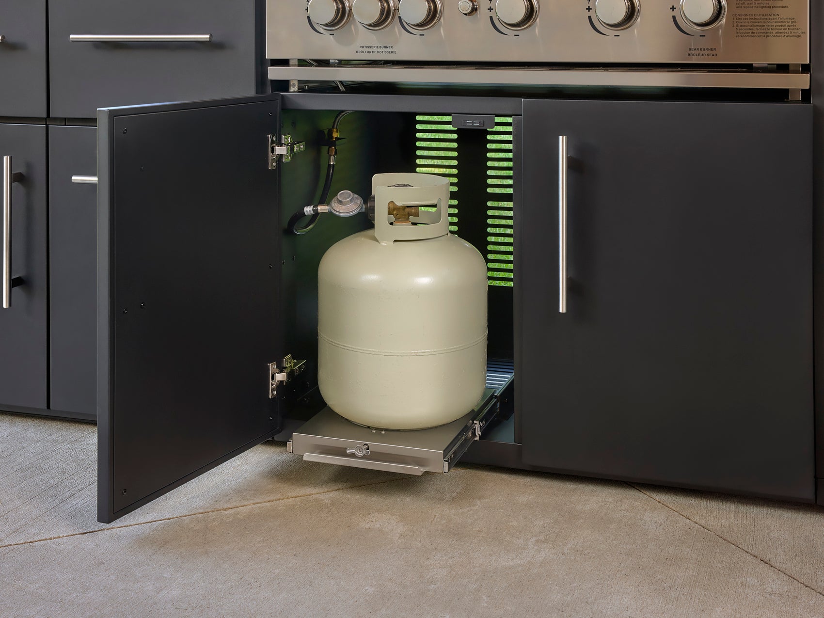 Propane tank stored in pullout cabinet drawer beneath Emory outdoor kitchen with black cabinetry and white countertop.