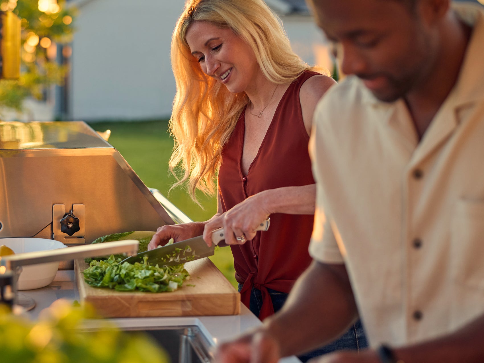 Couple preparing food outdoors on Range Outdoor Living Emory kitchen in backyard setting at sunset.