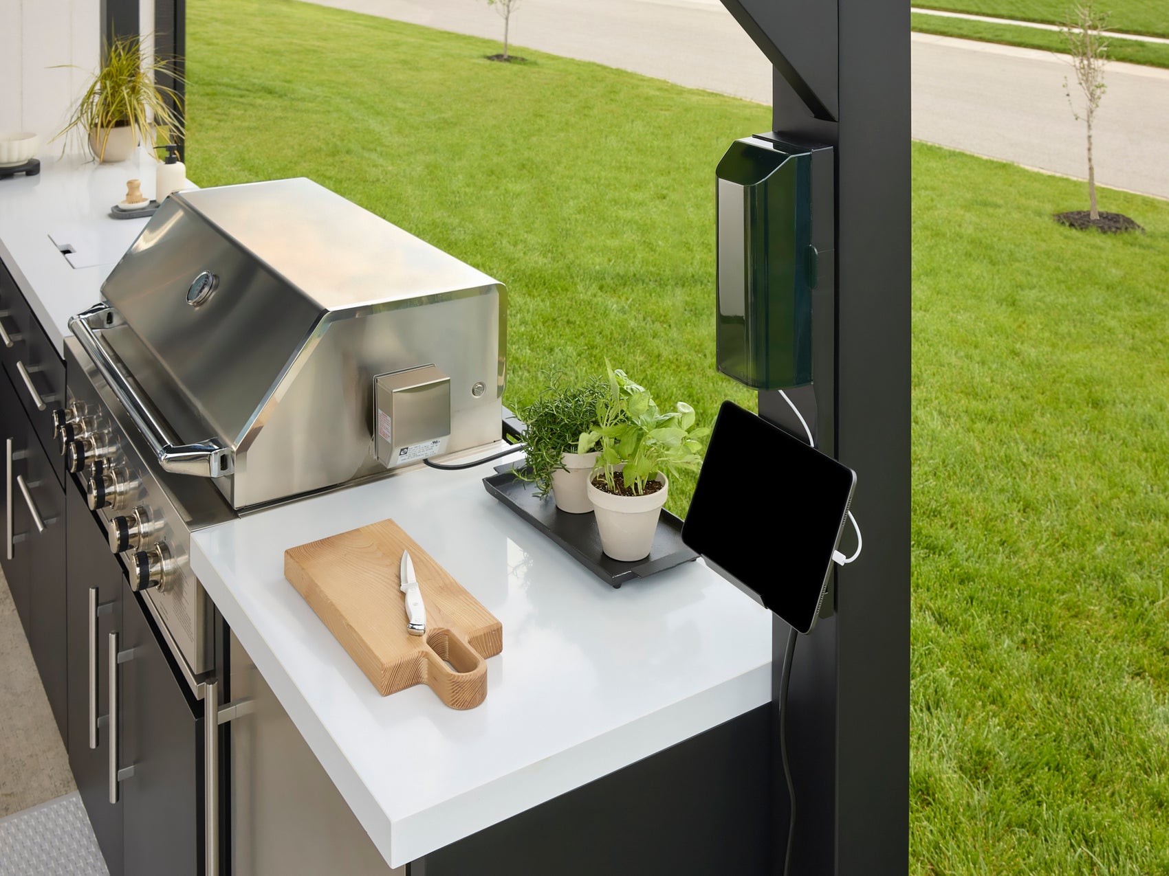 Lancaster Outdoor kitchen workspace with cutting board and tablet mounted on steel post with white countertop.