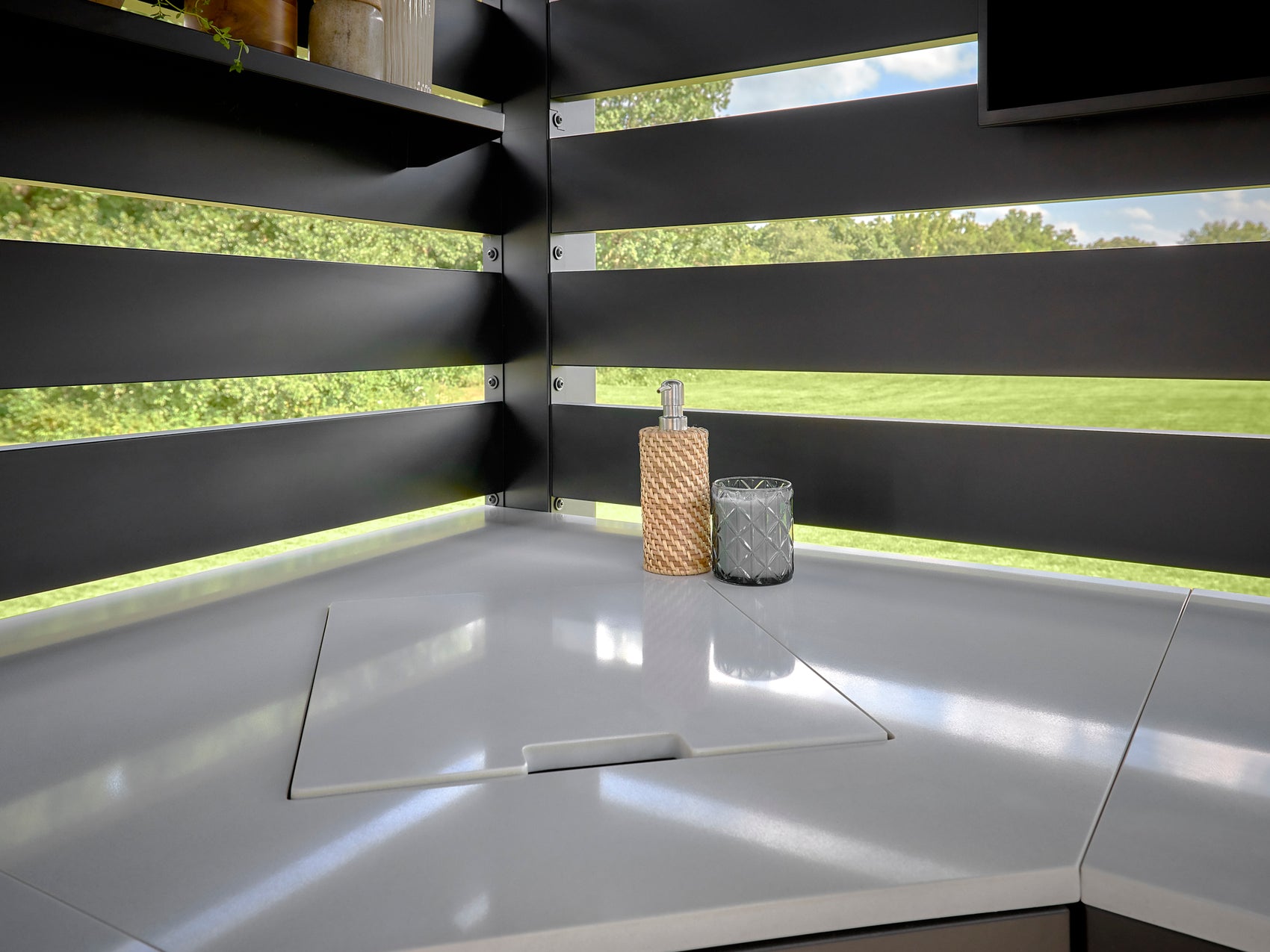 Langston Outdoor kitchen sink with matching accessories set into countertop with horizontal slat privacy screen.