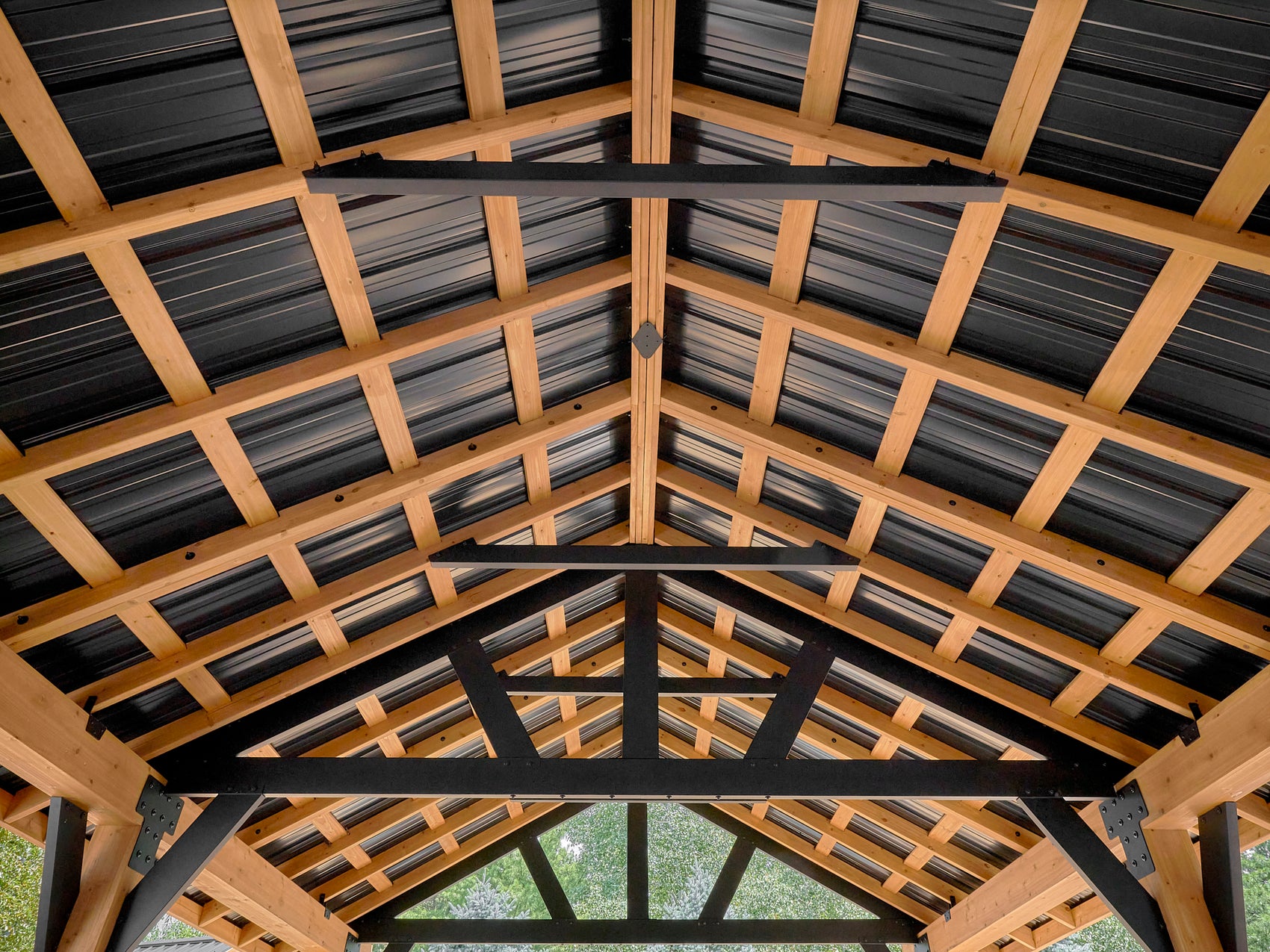 Interior view of Lodge deck gazebo with exposed timber frame, black metal roof panels, and decorative steel truss support.