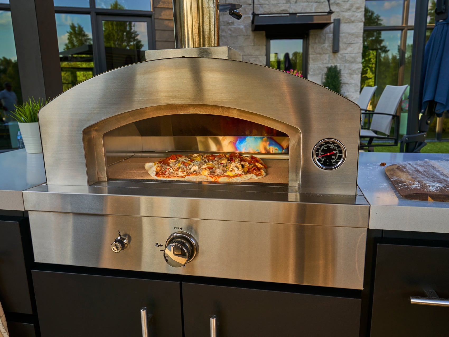 Range Outdoor Living artisan pizza oven with pizza cooking inside, built in to Edgemont Bay outdoor kitchen.