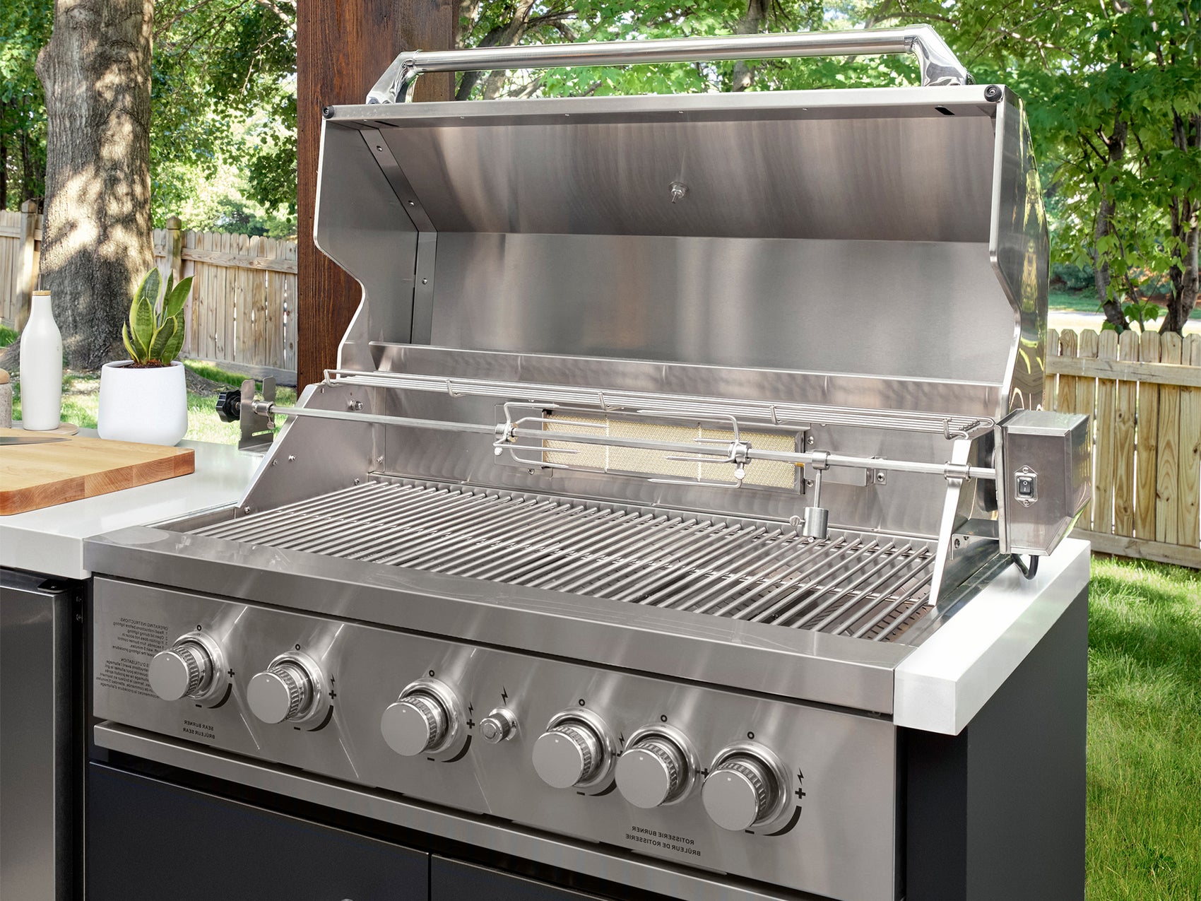 Open stainless grill with rotisserie burner and cooking grates on Emory outdoor grill island with engineered stone counter.