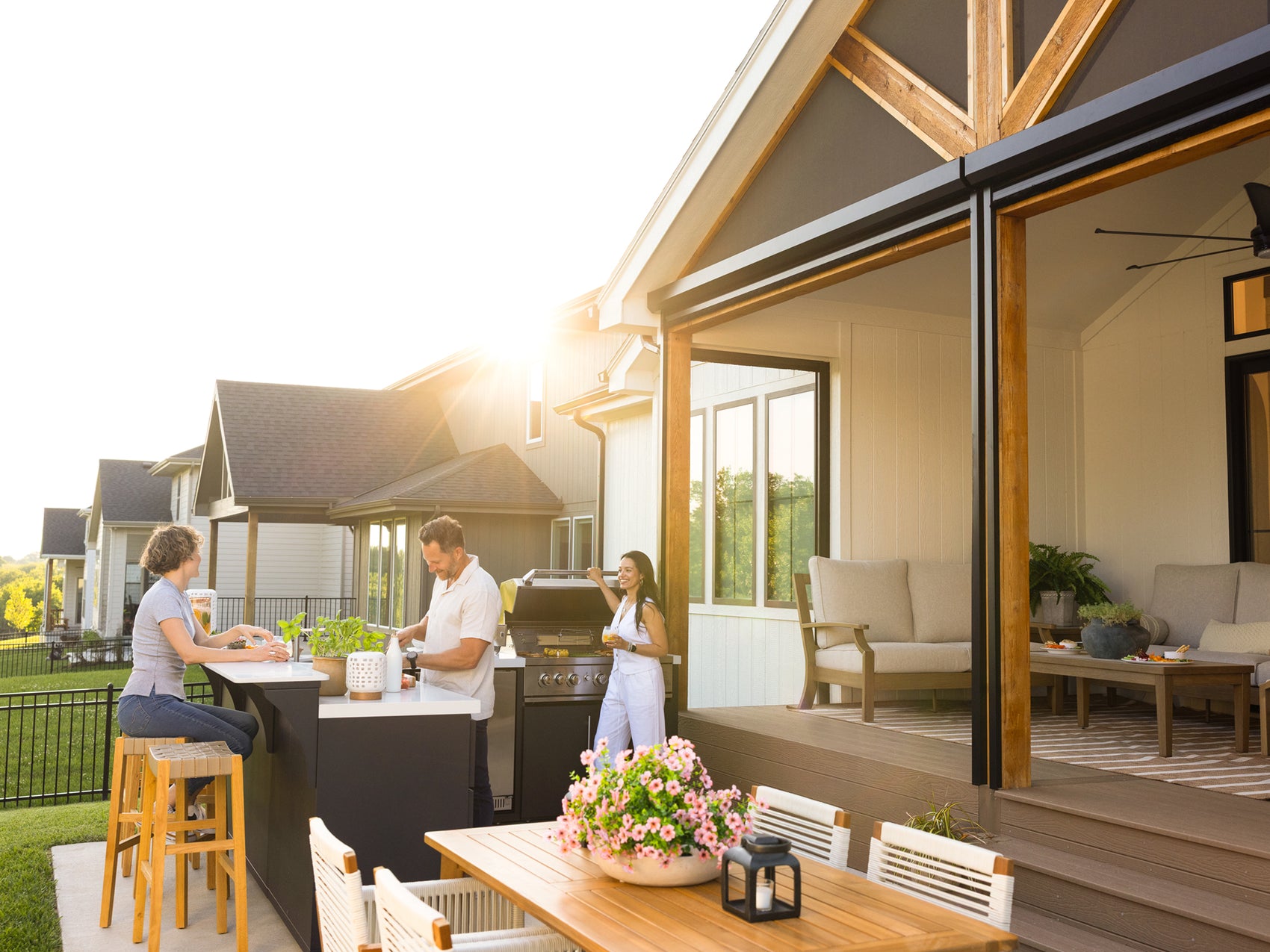 People cooking on the Emory outdoor kitchen with bar seating in backyard at sunset.