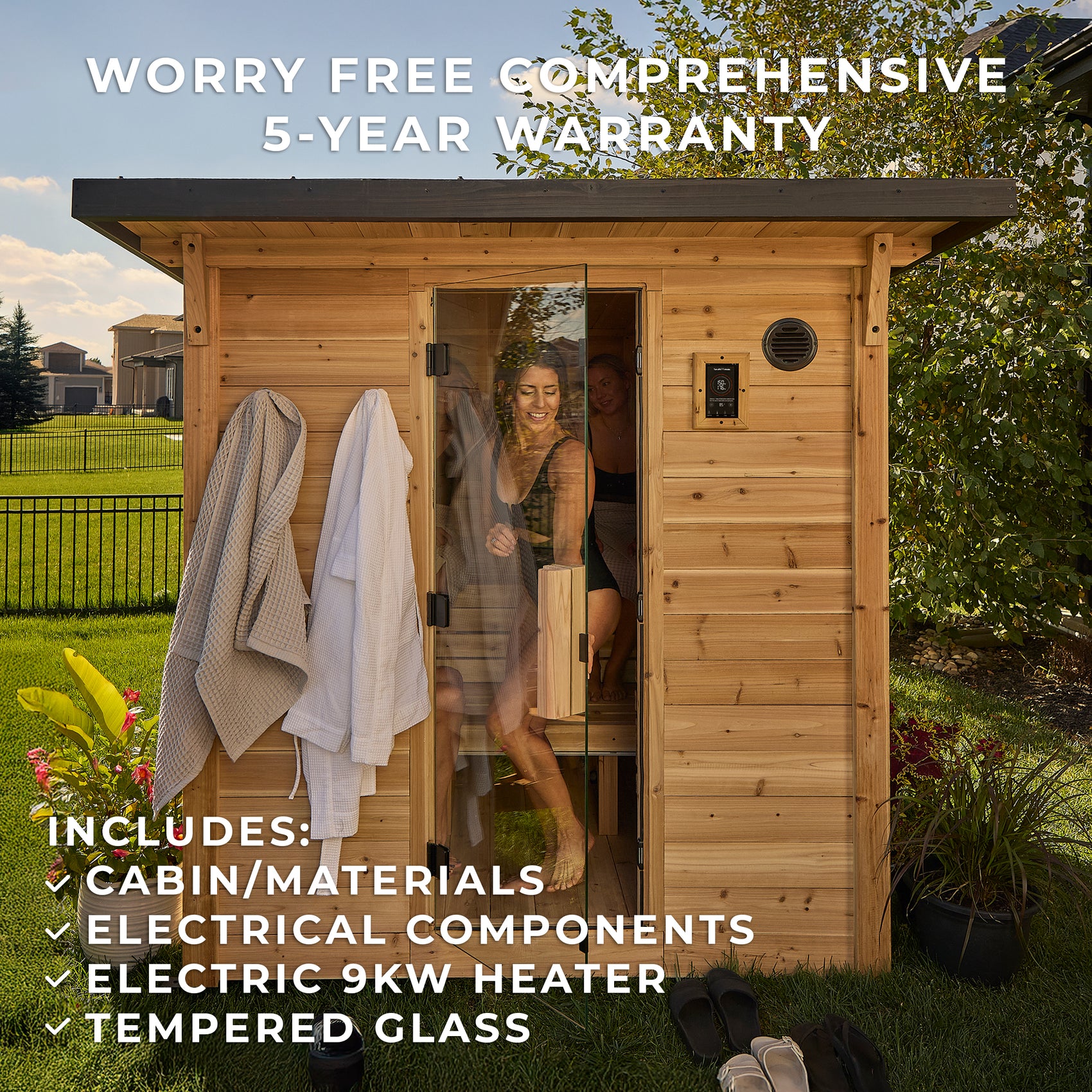 Two women enjoying outdoor home sauna session with robes and glass door open to backyard setting