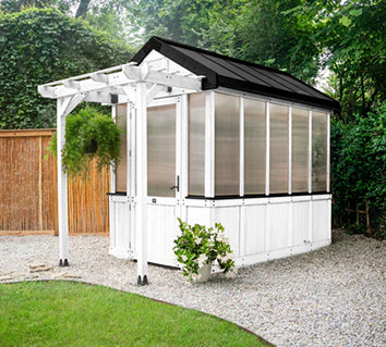 White cedar greenhouse kit with black trim, polycarbonate panels, and an integrated pergola. 
