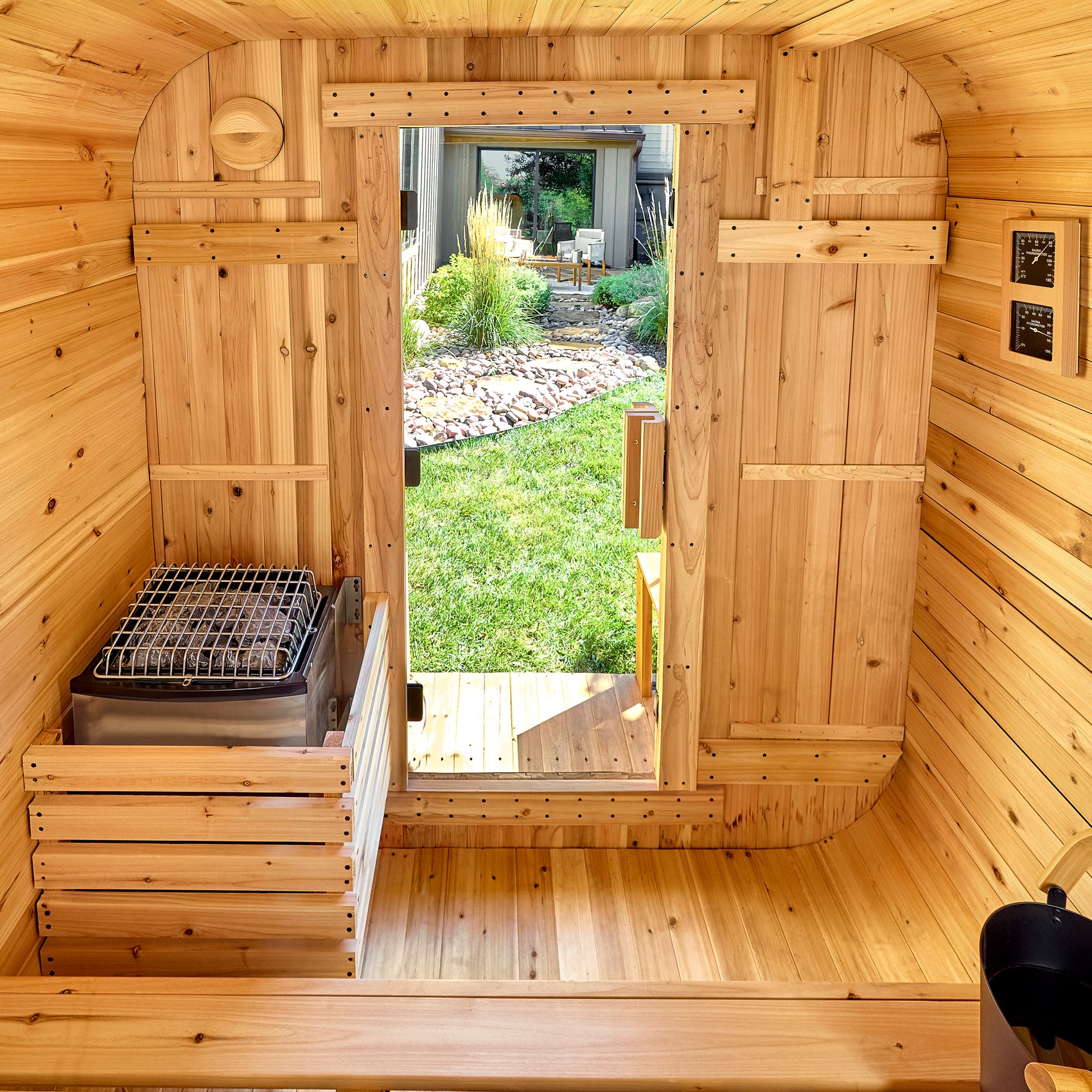 Interior view of the Lennon 4-6 person cube outdoor cedar sauna with electric stone heater for dry sauna sessions
