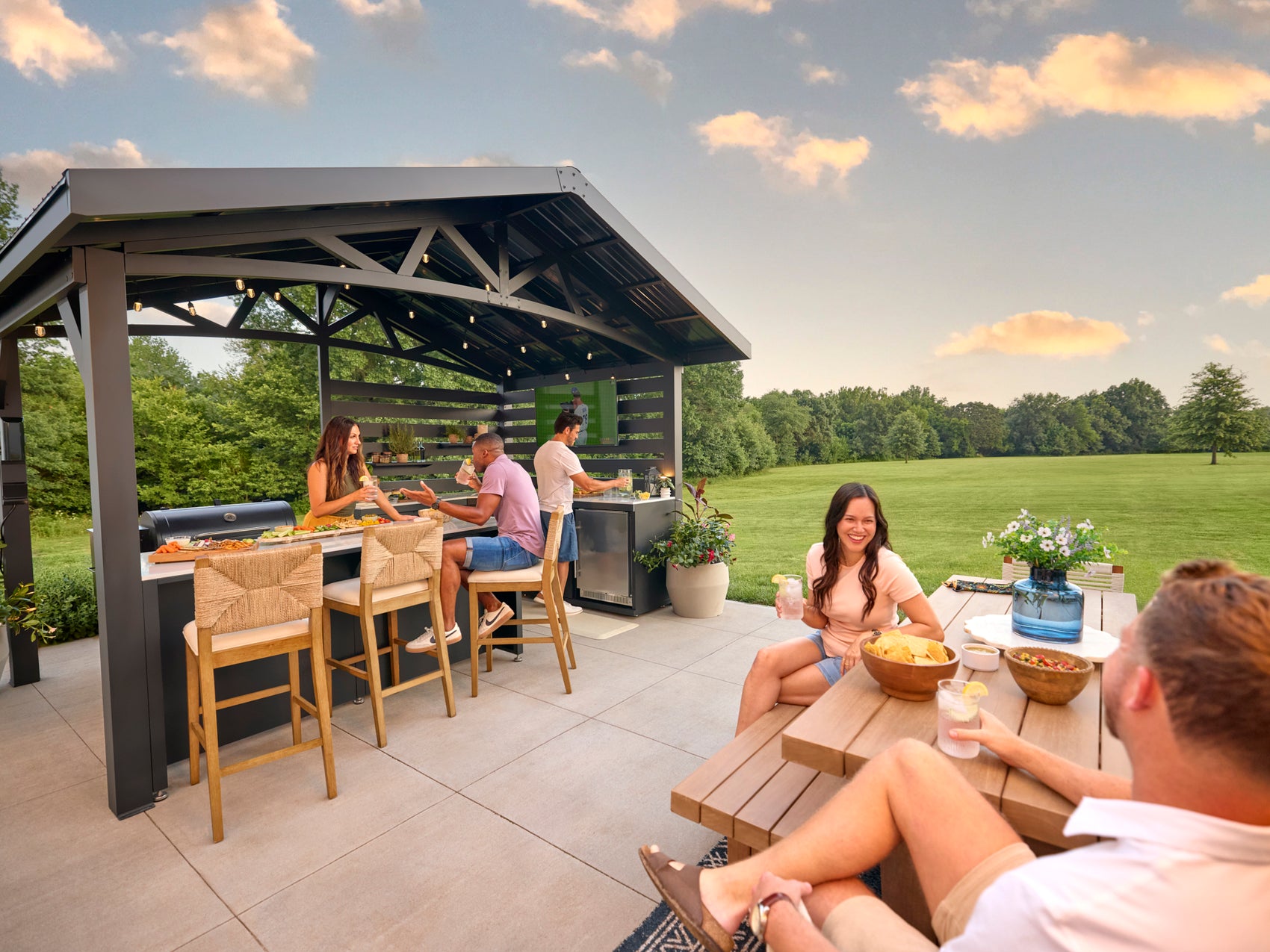 Range Outdoor Living Langston kitchen, bar seating, and dining area overlooking expansive green lawn.