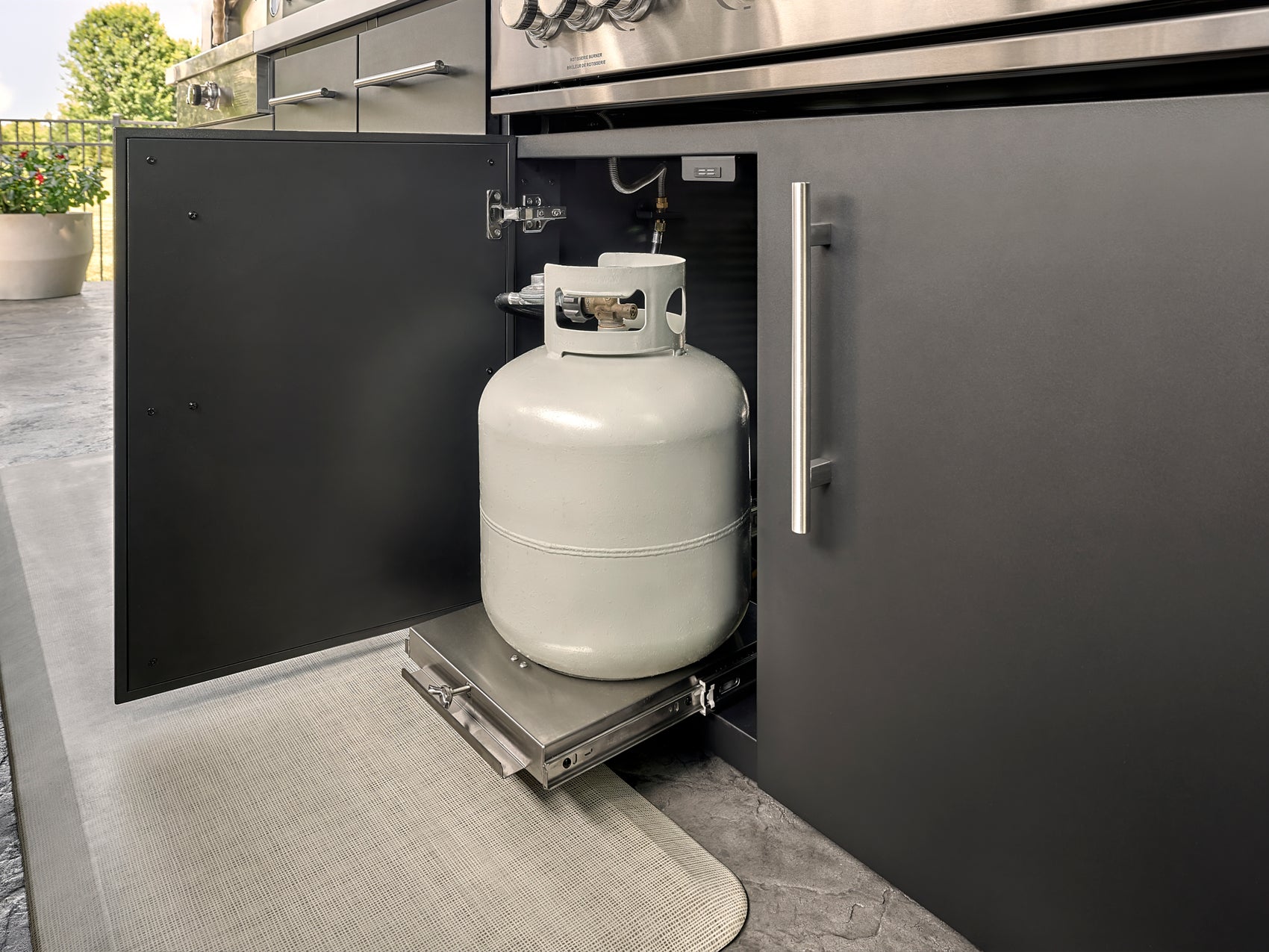 Lancaster Outdoor kitchen cabinet with pull-out propane tank storage drawer beneath built-in grill.