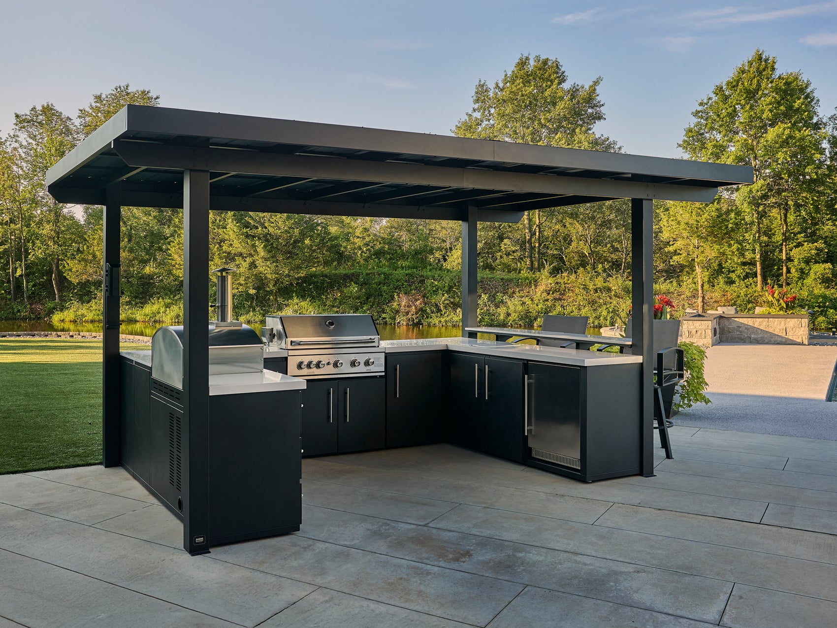 Edgemont Bay U-shaped patio kitchen with grill, pizza oven, and outdoor rated fridge under galvanized steel roof.