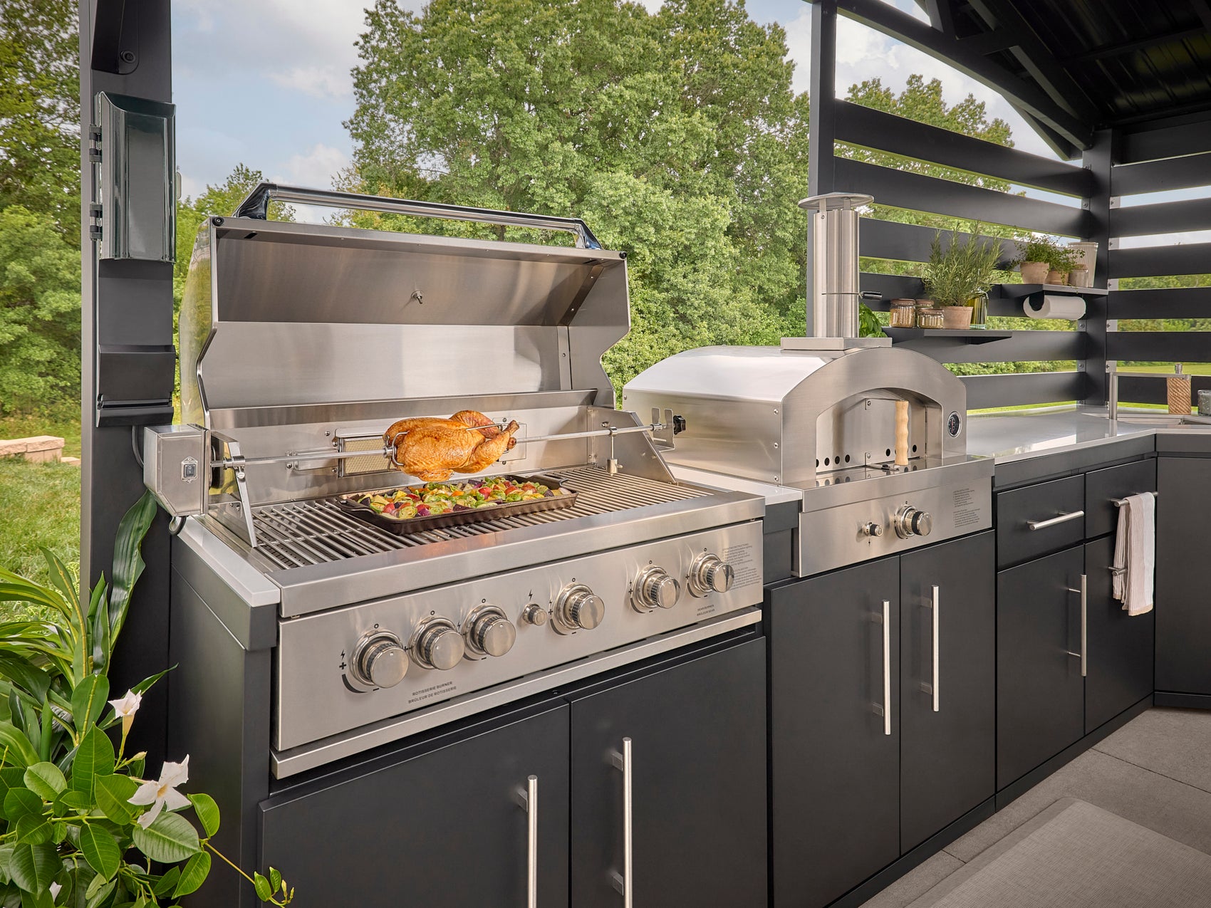 Range Outdoor Living built-in gas grill with rotisserie chicken and vegetables.