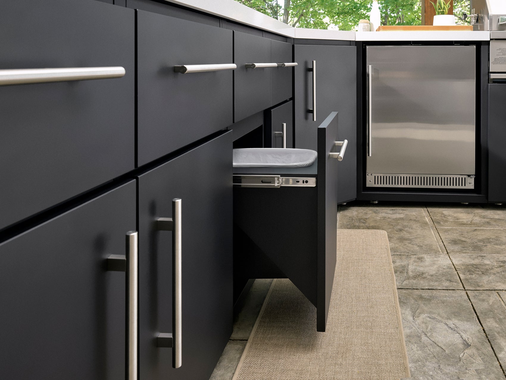 Emory modern outdoor kitchen with dark gray cabinets, brushed steel handles, pull-out trash drawer.