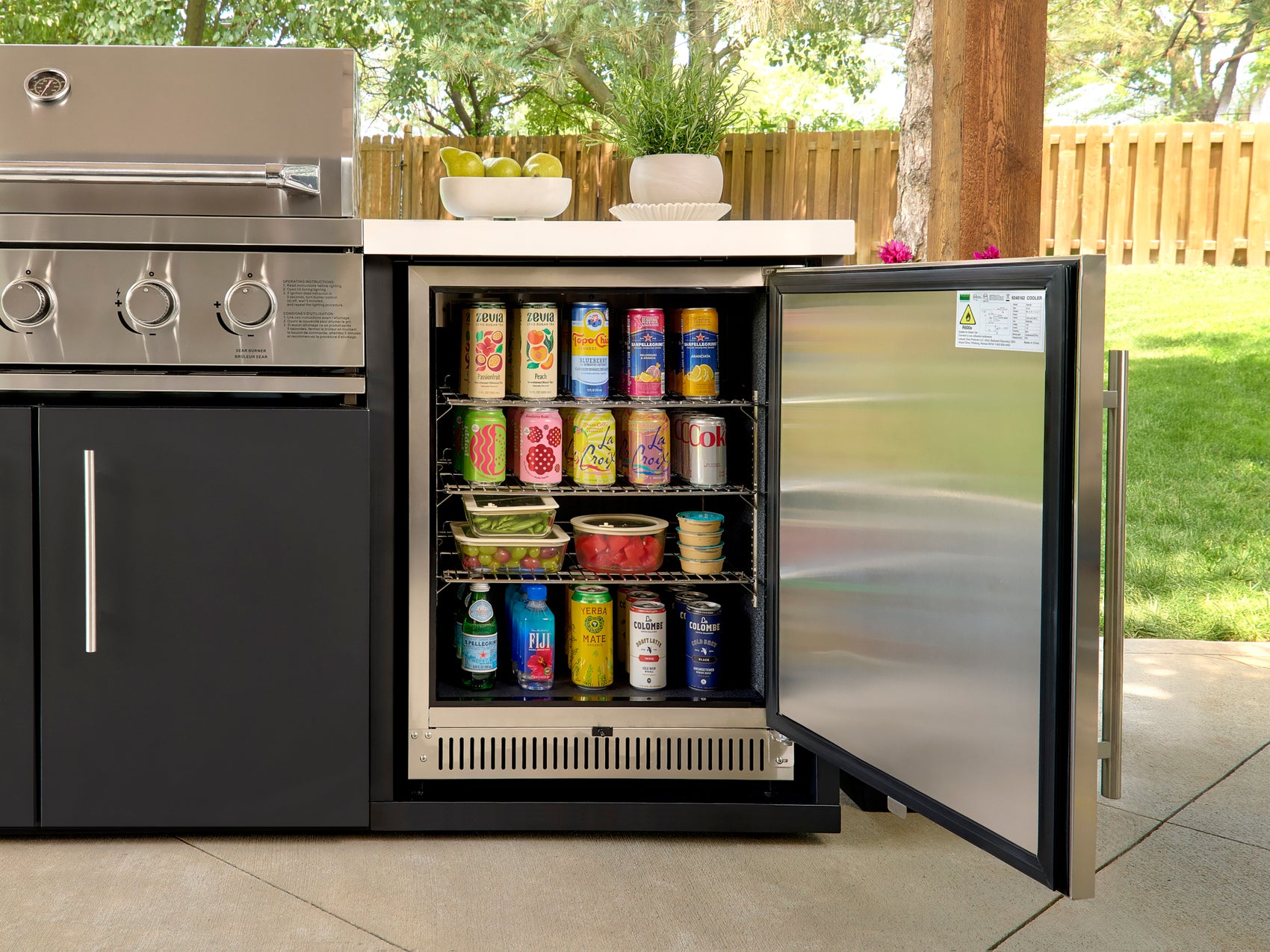 Range Outdoor Living Emory kitchen refrigerator with stainless steel door open revealing stocked shelves.