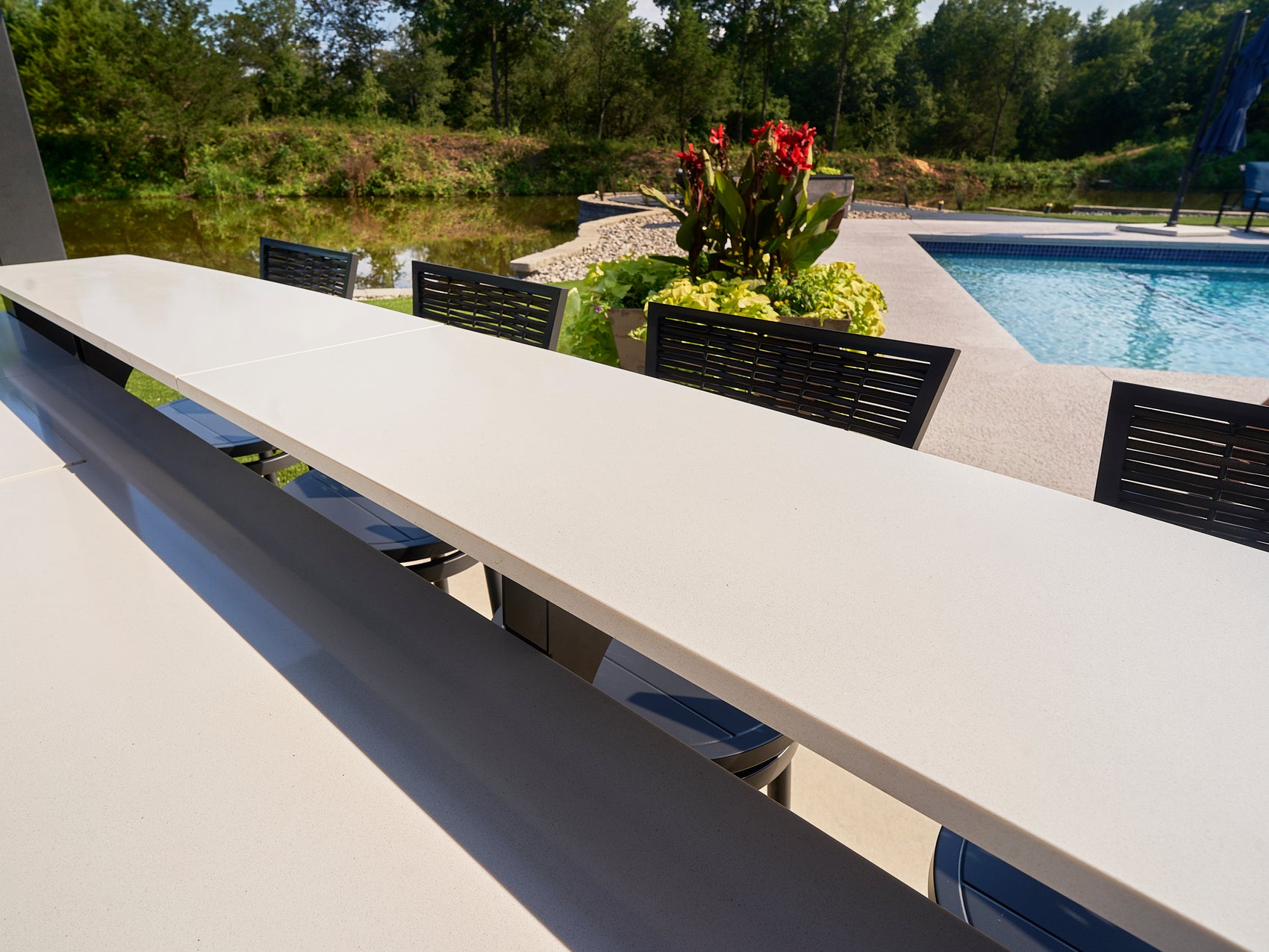 Edgemont Bay outdoor kitchen with built-in bar seating and pool in background.