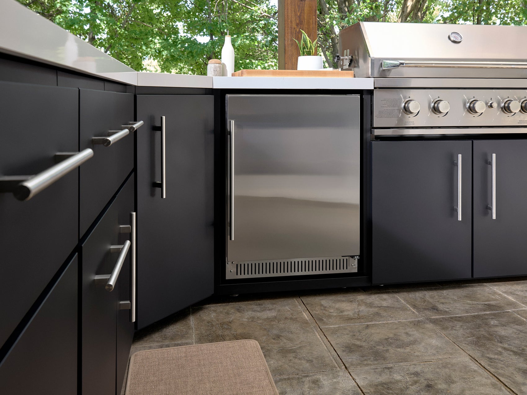 Range Outdoor Living refrigerator with stainless steel door in black cabinetry with brushed steel handles and tile flooring.