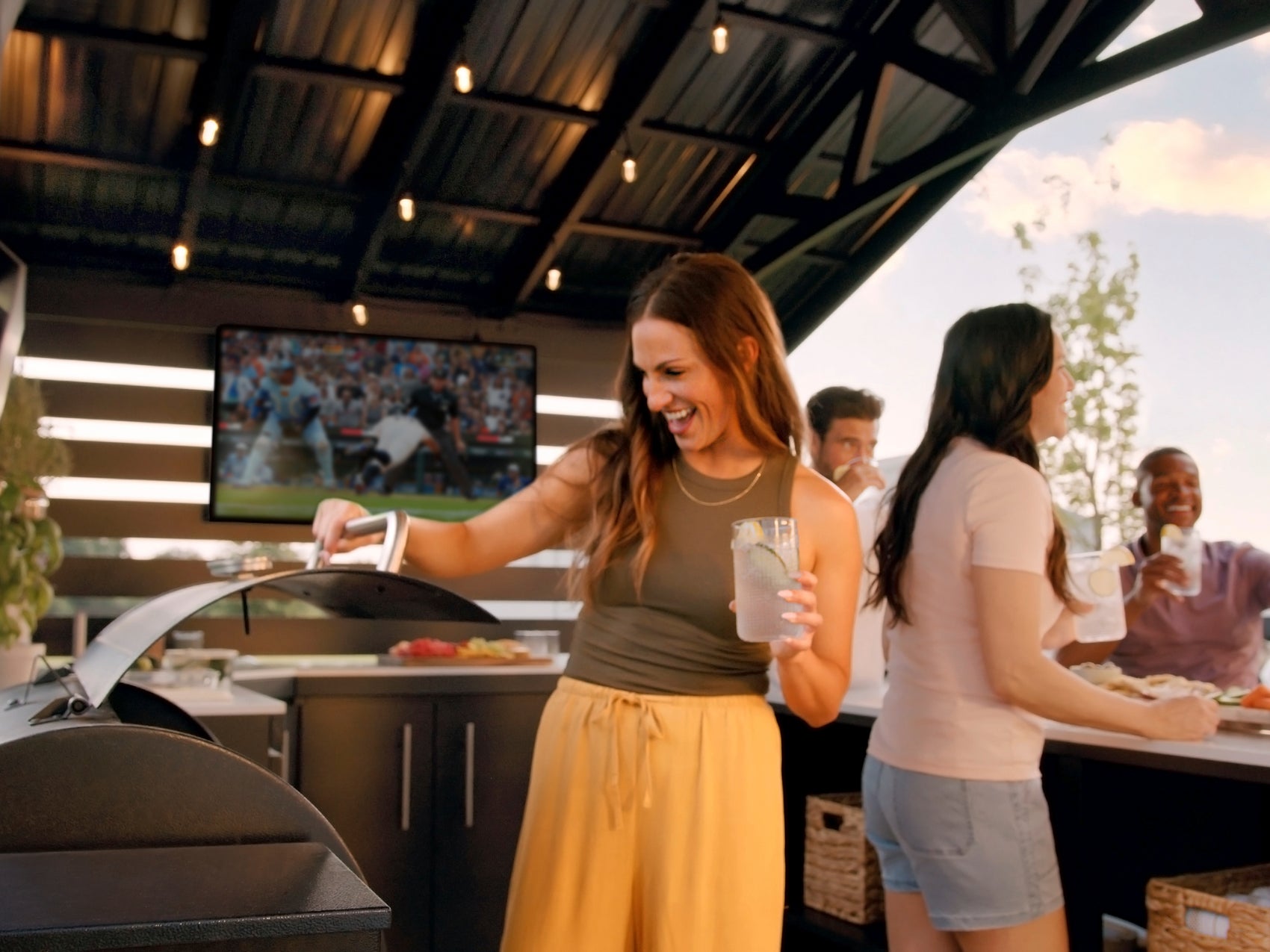 People gathering around Range Outdoor Living Langston kitchen with built-in appliances including grill.