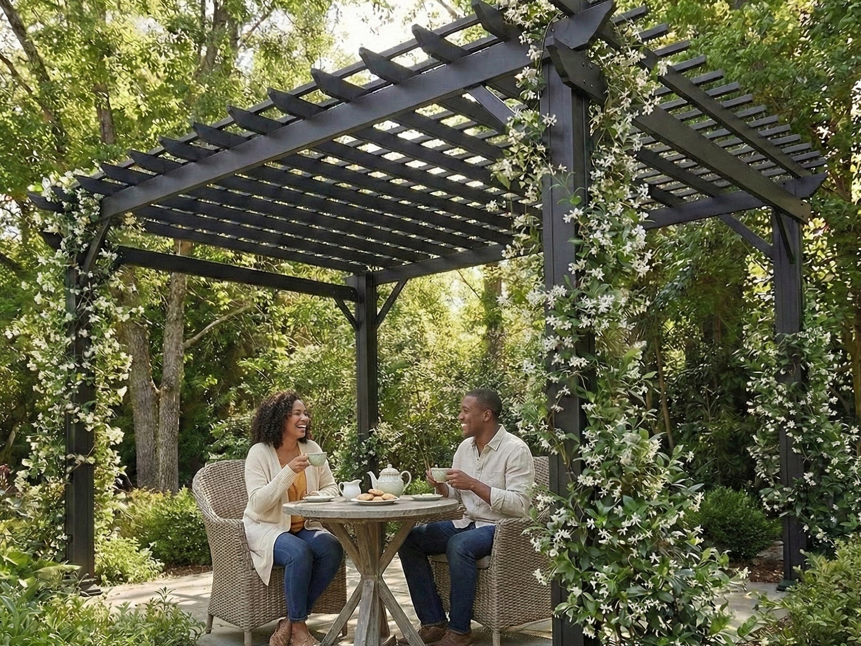 Black steel front Stratford porch pergola with trellis roof and climbing white flowers over couple enjoying tea.